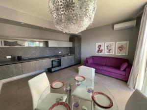 a living room with a glass table and purple couch at Polinesia 12 in Lido delle Nazioni +12 photos