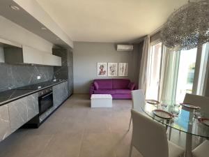 a living room with a purple couch and a glass table at Polinesia 12 in Lido delle Nazioni