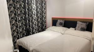 1 dormitorio con 1 cama con cortina en blanco y negro en Chez Rémy, en Yverdon-les-Bains