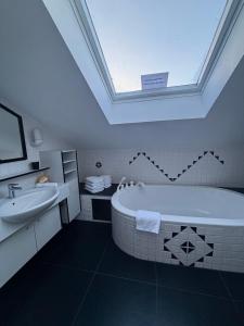 łazienka z wanną, umywalką i oknem dachowym w obiekcie RM-Apartments w mieście Innsbruck