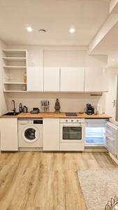 een keuken met witte kasten en een wasmachine en droger bij UG Neubau City Wohnung (Pool+Gym extra buchbar für €150/Tag) in München