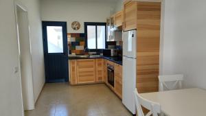 uma cozinha com armários de madeira e um frigorífico branco em La Caracola 3 Hab Con Solarium A 1min De La Playa em La Restinga