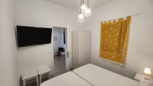 een kleine witte kamer met een tv aan de muur bij La Caracola 3 Hab Con Solarium A 1min De La Playa in La Restinga