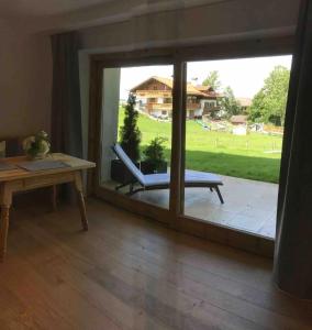 ein Raum mit einer Glasschiebetür mit einem Stuhl und einem Tisch in der Unterkunft Haus Hochland - Moderne Alpenwohnung Garten&Natur in Bad Kohlgrub + 11 Fotos