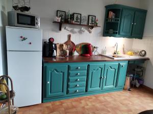 kuchnia z zielonymi szafkami i białą lodówką w obiekcie Villa Bellevue w mieście Venterol