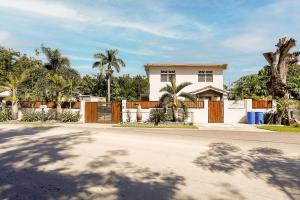 een wit huis met een hek en palmbomen bij EcoMar Rentals in Cabo Rojo
