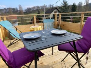 a black table with purple chairs and glasses on a deck at Au nid'Elma in Breitenau