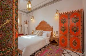 a bedroom with a large bed with an ornate headboard at Riad Fes Madaw in Fez