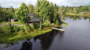 a small boat in a river next to a house at Karhunhovi in Pääjärvi