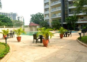 a patio with chairs and tables and palm trees at Mason apartments, ikoyi in Lagos