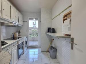 uma pequena cozinha com armários brancos e uma janela em Le Cosy Wiener *Paris*Gare à 300 m*Disneyland* em Champs-Sur-Marne