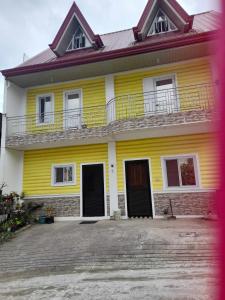 een geel huis met een balkon erboven bij MountainFog Transient House in Baguio