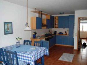 a kitchen with blue cabinets and a table and chairs at FeWo Möwennest Felstehausen GM 69252 in Graal-Müritz