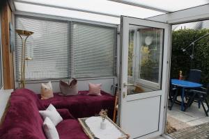 a screened in porch with a purple couch and pillows at Haus 2 - Haus Behaglich Heinrich GM 69368 in Graal