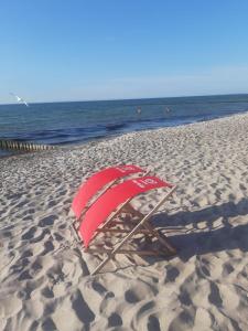 a red umbrella sitting on a beach next to the ocean at Ostseebuhne GM Schwerdtner in Müritz
