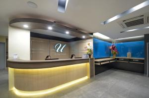 a hotel lobby with a reception counter with two people at U Design Hotel Bukit Mertajam in Bukit Mertajam