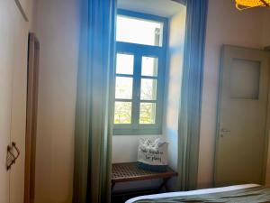 a bedroom with a window and a bed with blue curtains at Aegina Town Home in Egina