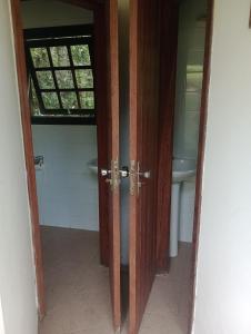 a door to a bathroom with a window and a sink at Gran Camping Cabanas da Fazenda in Visconde De Maua