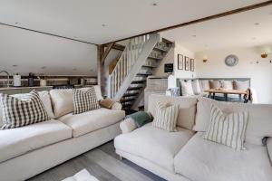 a living room with two white couches and a staircase at Oak Tree Hideaway in Whitchurch