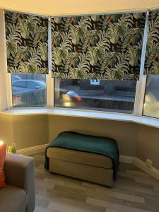 a room with two large windows with a green ottoman at Affordable Newly Refurbished 3 Bedroom House, Sleeps 7, NG8 Postcode in Nottingham