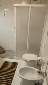 y baño blanco con aseo y ducha. en Casa Mafalda, en Aradeo