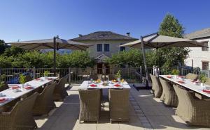 um pátio com mesas, cadeiras e guarda-sóis em Zagori Suites Luxury Residences em Vitsa