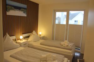 two beds in a hotel room with a window at Meereszeit - OlpenitzResort in Olpenitz