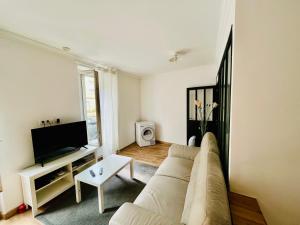 uma sala de estar com um sofá e uma televisão em Appartement 2 pièces, proche RER, Bus et chateau em Rambouillet