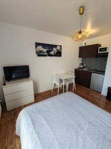 a bedroom with a bed and a table and a kitchen at Studio Disneyland Paris 10min/Val d'Europe 5min/Wifi/TV in Montévrain