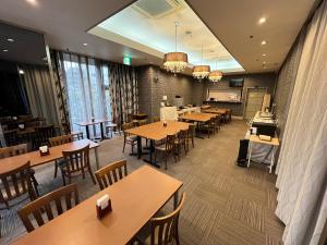 a restaurant with wooden tables and chairs and windows at Royal Hotel Uohachi in Toyota