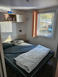 Cama en habitación con ventana en Mobil home 6 personnes en Saint-Brevin-les-Pins
