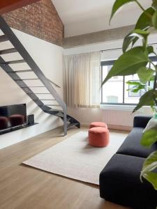 a living room with a black couch and a staircase at Unique design triplex with rooftop terrace in Mechelen