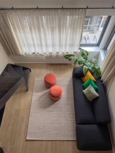 a living room with a black couch with colorful pillows at Unique design triplex with rooftop terrace in Mechelen