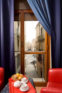 Mammasisi Rooms في ليتشي: صينية حمراء مع وعاء من الفواكه على طاولة بالقرب من النافذة