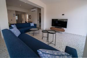 a living room with a blue couch and a tv at City House - Hersonissos Center - Sleeps 8 in Hersonissos