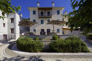 un edificio con dos sombrillas delante en Zagori Suites Luxury Residences, en Vitsa