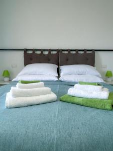 a bed with white pillows and green towels on it at Puzzle Rooms in Campobasso