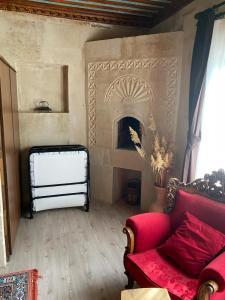 uma sala de estar com lareira e um sofá vermelho em Cappadocia Cave Sinasos Villa em Mustafapaşa