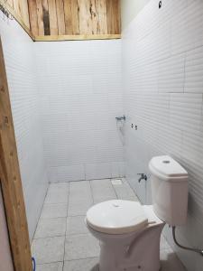 ein Bad mit WC und weißen Fliesen in der Unterkunft First Mayor' Garden in Malamagambo