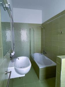 a green tiled bathroom with a tub and a sink at Puzzle Rooms in Campobasso +10 photos