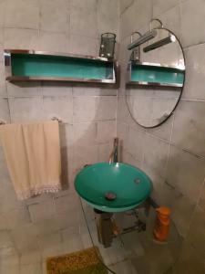 baño con lavabo verde y espejo en B&b La Palma, en Sferracavallo