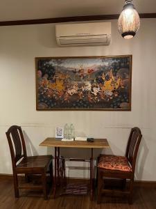 una mesa con dos sillas y un cuadro en la pared en Around The World Bed and Breakfast, en Bangkok