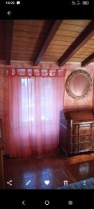 Habitación con cortinas rojas, mesa y espejo. en Soledad, en Bonassola