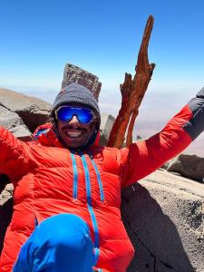 a man in a red jacket sitting on the beach at Xperience Hostel in San Pedro de Atacama +4 photos