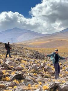two people standing on a rocky hill with mountains in the background at Xperience Hostel in San Pedro de Atacama