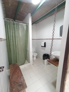 La salle de bains est pourvue d'un rideau de douche vert et de toilettes. dans l'établissement Posada Chambranas, à Salento