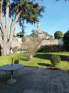 una mesa sentada en un patio junto a un árbol en Le clos du prieuré, en Montjean-sur-Loire