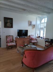 a living room with chairs and a tv and a table at Le clos du prieuré in Montjean-sur-Loire