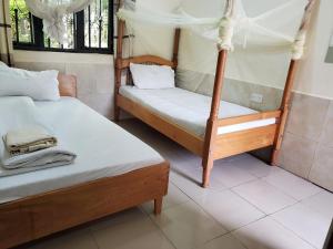 1 dormitorio con 2 camas con sábanas blancas en Mackline Rest House, en Rubirizi