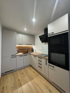 a kitchen with white cabinets and a black microwave at Apartman Amur in Košice